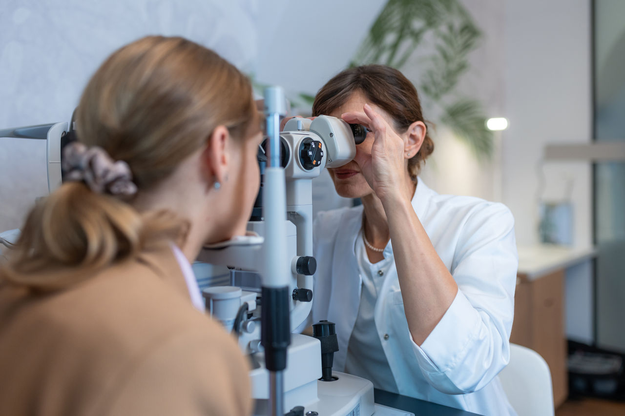 An optometrist in an ophthalmic clinic performs an eye examination on a device for measuring diopters, examination of the fundus of the eye, gray and yellow cataracts, examination of the tear ducts. She reads the data from the tablet and from the computer screen.